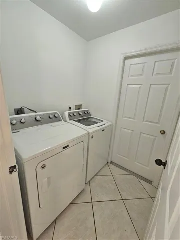 Laundry room with light tile patterned flooring and washer and dryer