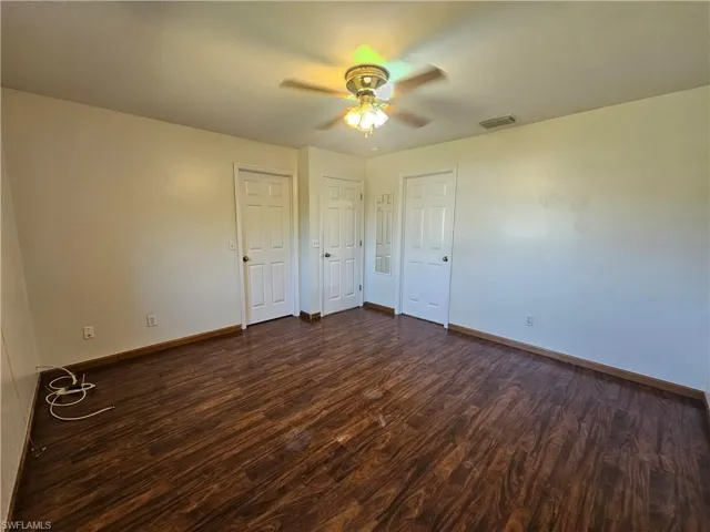 Unfurnished bedroom with ceiling fan, hardwood / wood-style flooring, and multiple closets