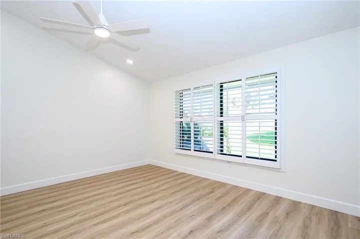 Empty room featuring ceiling fan, lofted ceiling, and light hardwood / wood-style flooring