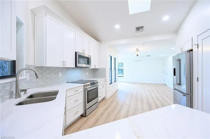 Kitchen featuring white cabinetry and appliances with stainless steel finishes