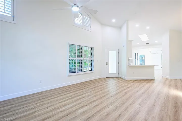 Unfurnished living room featuring light hardwood / wood-style floors, a high ceiling, a wealth of natural light, and a skylight