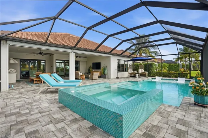 View of pool with a lanai, a pool with connected hot tub, a sunroom, and a patio