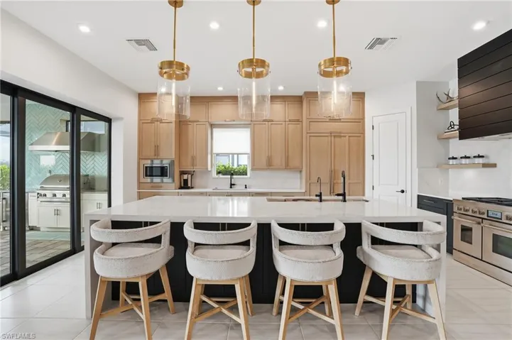 Kitchen with light stone counters, a large island, recessed lighting, appliances with stainless steel finishes, and extractor fan