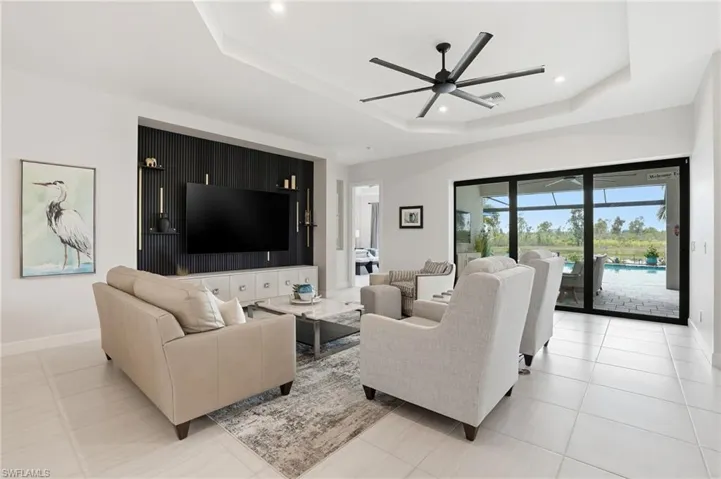 Living area featuring a tray ceiling, a ceiling fan, recessed lighting, and light tile patterned flooring