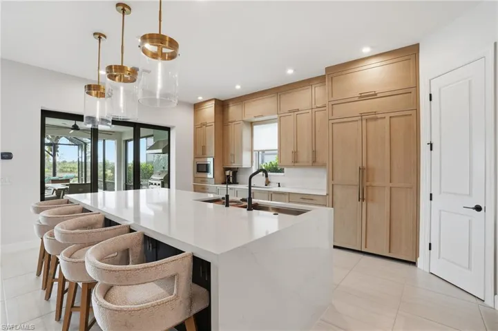 Kitchen with a kitchen bar, a spacious island, healthy amount of natural light, light brown cabinetry, and recessed lighting