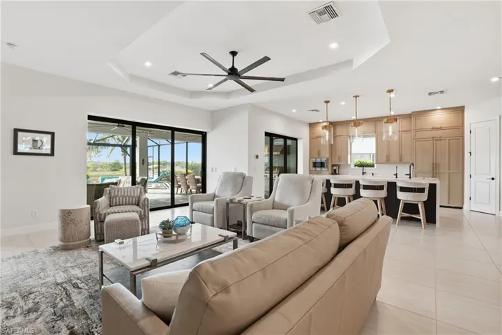 Living area featuring healthy amount of natural light, a tray ceiling, a ceiling fan, light tile patterned floors, and recessed lighting