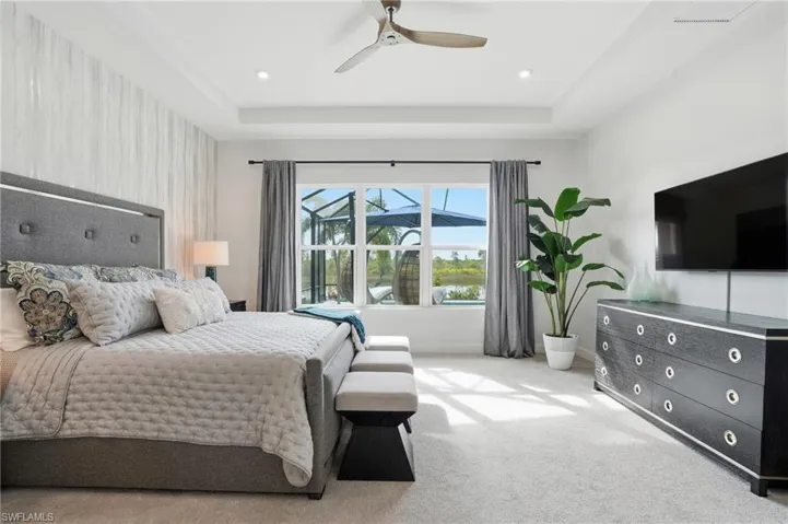 Bedroom featuring carpet, a ceiling fan, and a raised ceiling