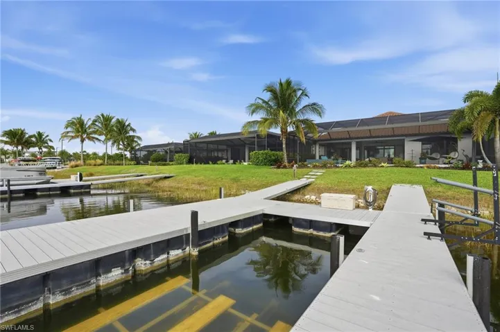 Dock featuring a sunroom, a water view, a lawn, and glass enclosure
