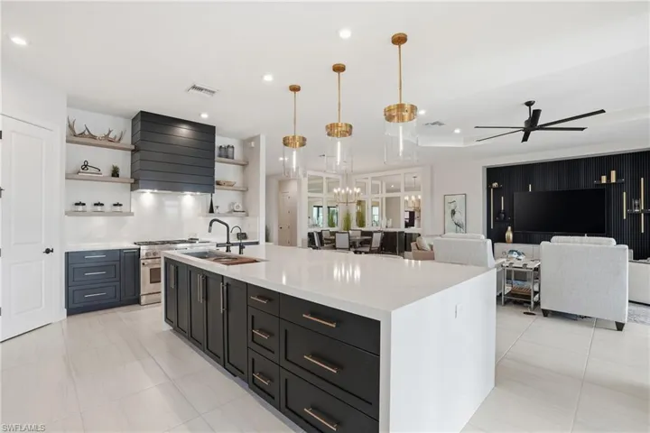Kitchen with hanging light fixtures, a spacious island, dark cabinets, custom exhaust hood, and open floor plan