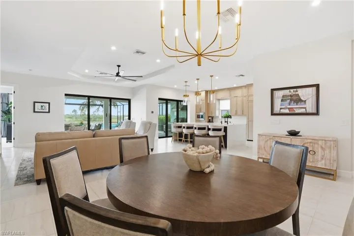 Dining room featuring a ceiling fan, recessed lighting, a tray ceiling, a chandelier, and light tile patterned floors