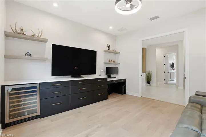Living room with wine cooler, light wood finished floors, built in desk, and recessed lighting