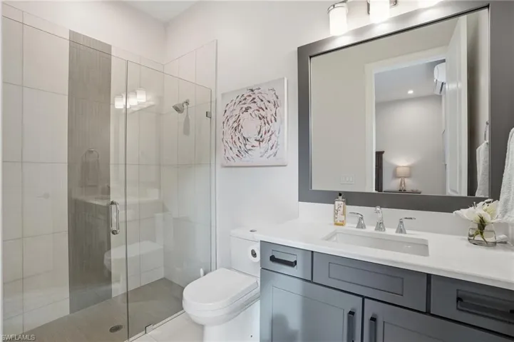 Bathroom with vanity, a shower stall, and a wall mounted AC