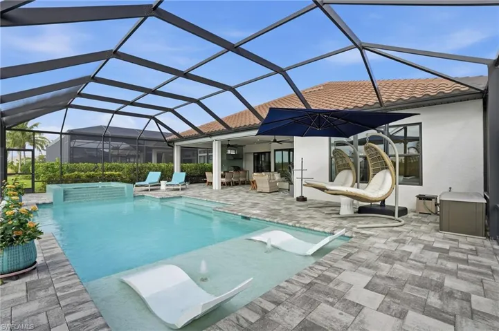 Outdoor pool with glass enclosure, a sunroom, a patio, and a jacuzzi