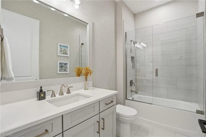 Bathroom with vanity and bath / shower combo with glass door