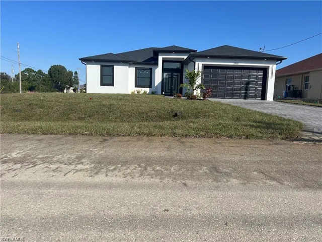 View of front of house with an attached garage, a front yard, decorative driveway, and stucco siding