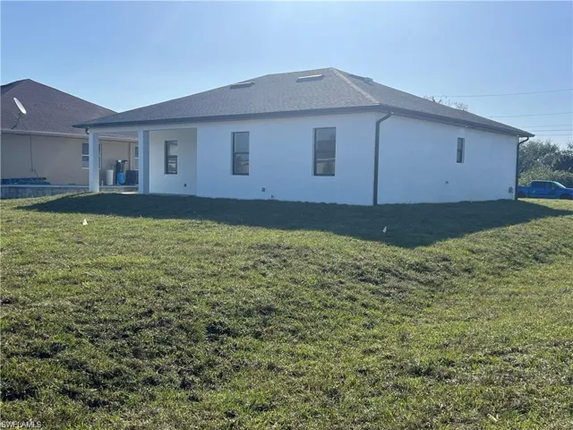 Back of house with a yard and stucco siding
