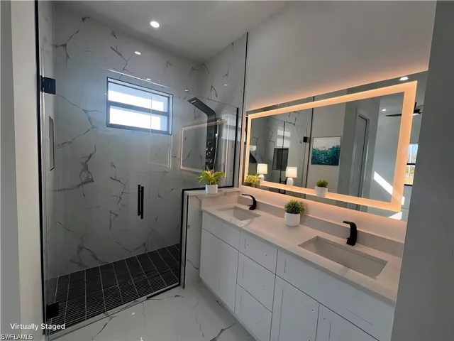 Virtually Staging Bathroom with double vanity, marble finish floor, a marble finish shower, and a sink