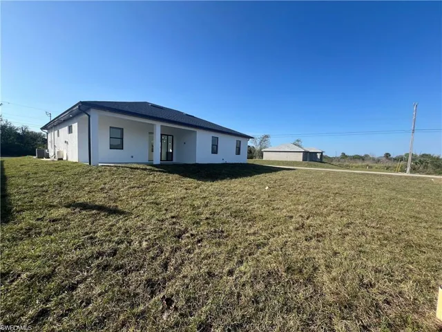 View of front of house featuring a front yard, cooling unit, and stucco siding