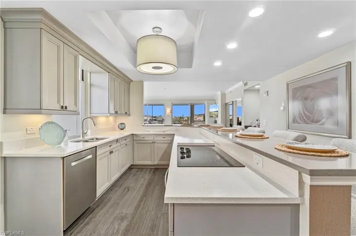 Kitchen with light wood finished floors, recessed lighting, light stone countertops, and a raised ceiling