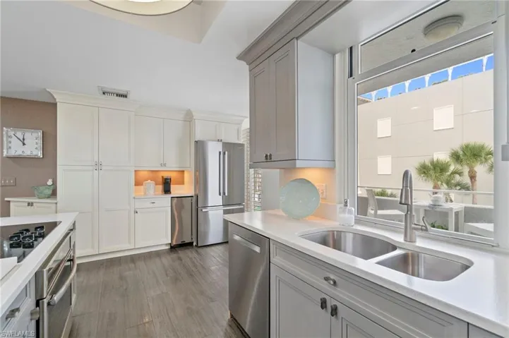 Kitchen featuring stainless steel appliances, dark wood-style flooring, light stone counters, and gray cabinetry