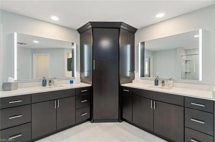 Full bathroom featuring two vanities, a shower, and recessed lighting