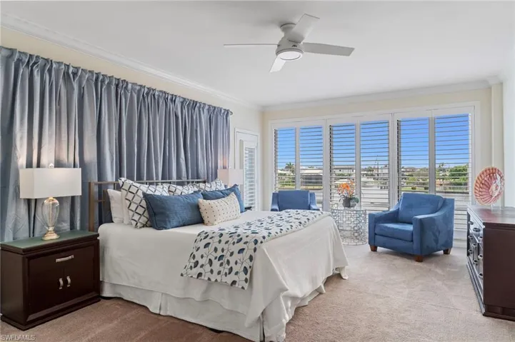Bedroom with light colored carpet, ornamental molding, and a ceiling fan