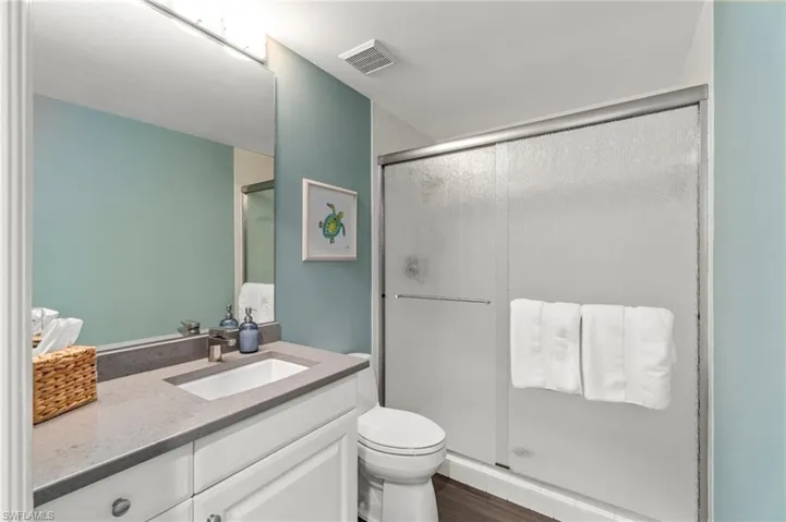 Full bathroom with a shower stall, vanity, and dark wood finished floors