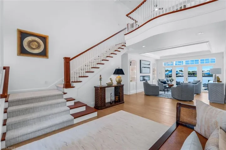 Stairs featuring wood finished floors, a towering ceiling, a water view, and a tray ceiling