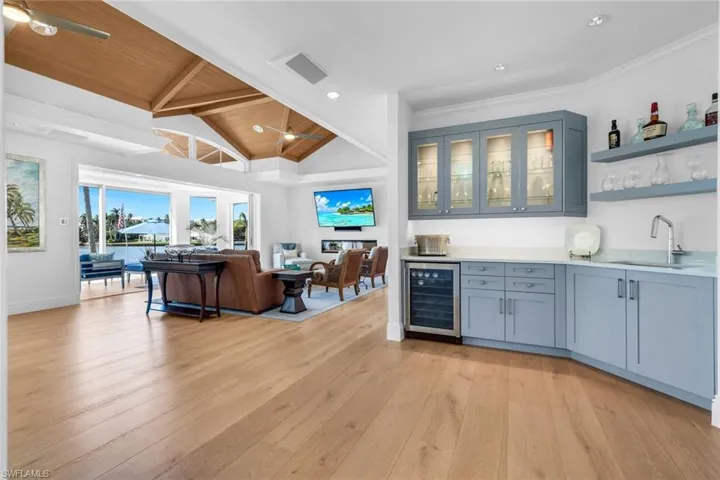Indoor wet bar featuring open shelves, glass insert cabinets, beverage cooler, light wood finished floors, and recessed lighting