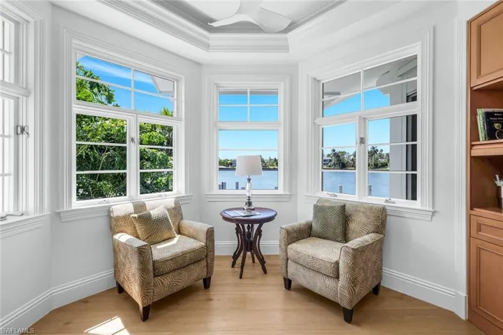 Living area with wood finished floors, a water view, plenty of natural light, and ornamental molding
