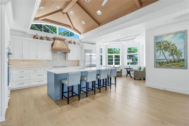 Kitchen featuring a breakfast bar, white cabinets, a center island with sink, recessed lighting, and built in refrigerator