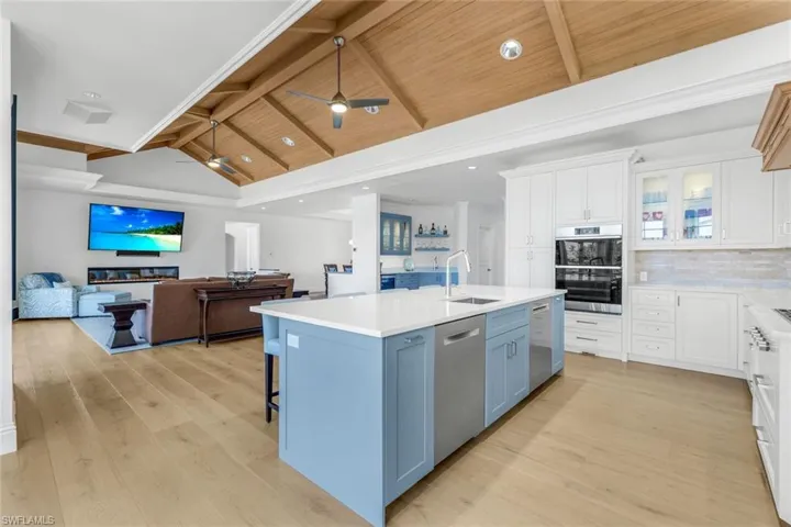 Kitchen with open floor plan, glass insert cabinets, white cabinets, a kitchen breakfast bar, and recessed lighting
