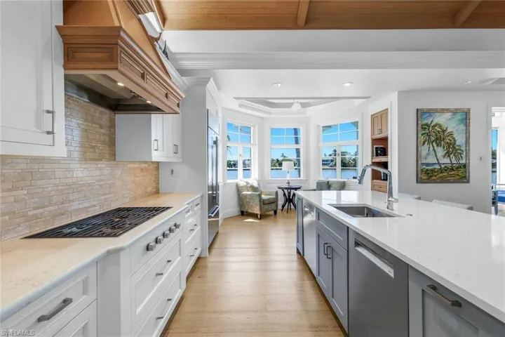 Kitchen with light stone countertops, white cabinets, premium range hood, beamed ceiling, and recessed lighting