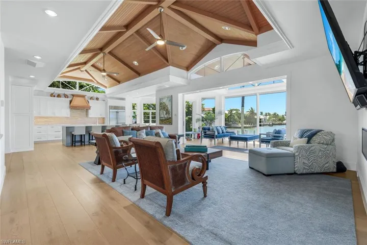 Living area with high vaulted ceiling, light wood-type flooring, built in desk, recessed lighting, and a wooden ceiling with exposed beams