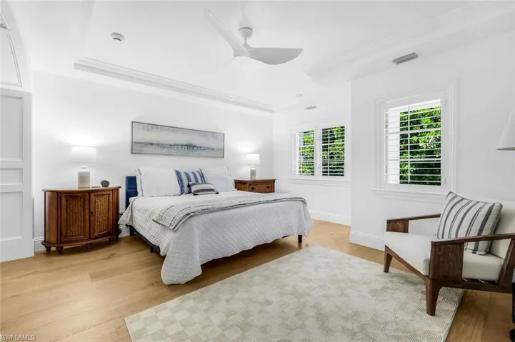 Bedroom featuring light wood finished floors, ornamental molding, a ceiling fan, and a raised ceiling