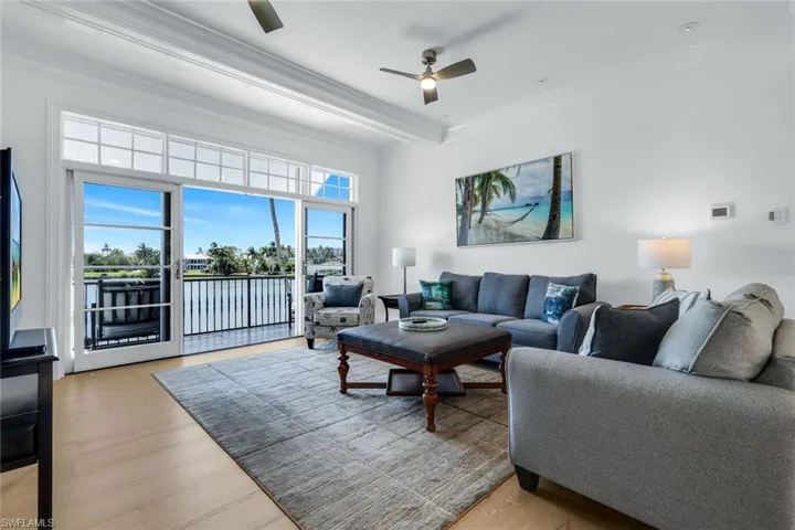 Living room featuring light wood-type flooring, crown molding, a ceiling fan, and a water view