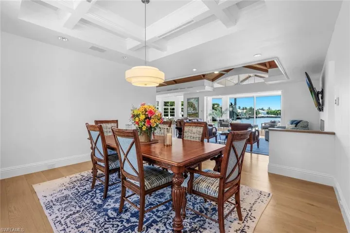 Dining space featuring beamed ceiling, coffered ceiling, light wood-style flooring, and french doors