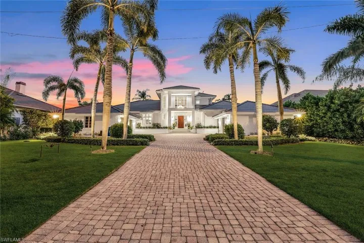 View of front of house with decorative driveway, stucco siding, and a front lawn