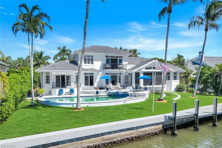 Back of house with a yard, a patio area, an outdoor pool, and a water view