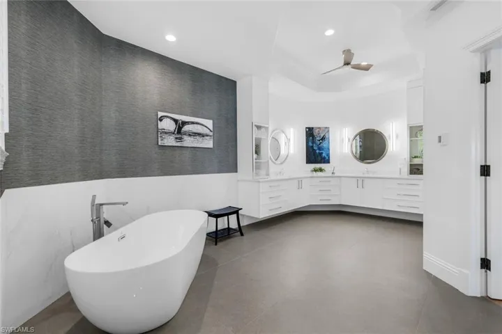 Full bathroom featuring a freestanding bath, vanity, recessed lighting, wainscoting, and wallpapered walls