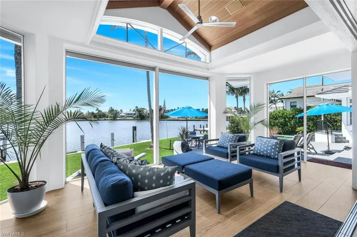 Sunroom / solarium featuring a water view, a wooden ceiling with exposed beams, wood finished floors, healthy amount of natural light, and high vaulted ceiling