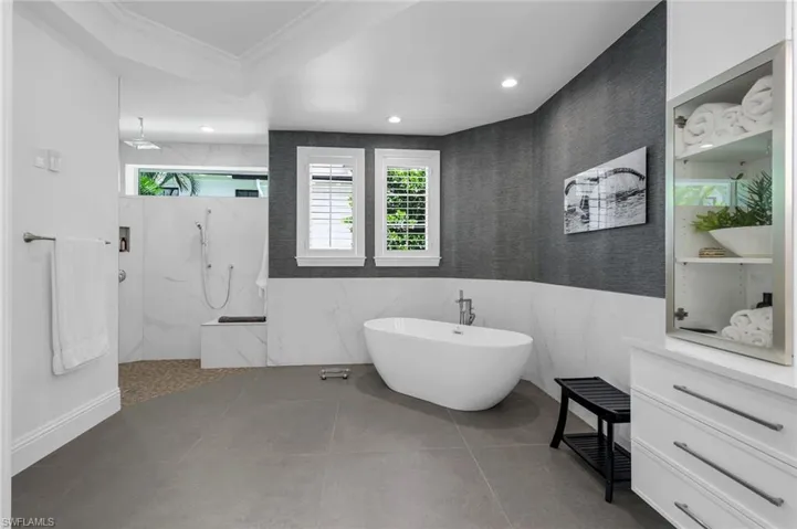 Full bathroom featuring a soaking tub, tile walls, ornamental molding, a marble finish shower, and recessed lighting