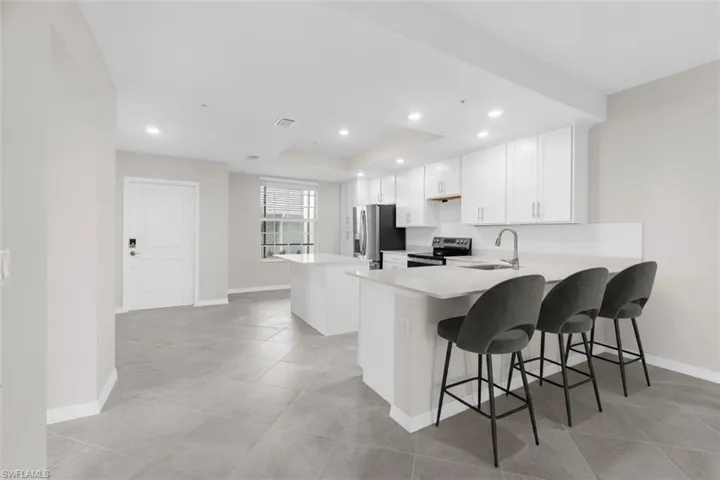 Kitchen featuring white cabinetry, light-toned countertops, a stainless steel sink, and recessed lighting