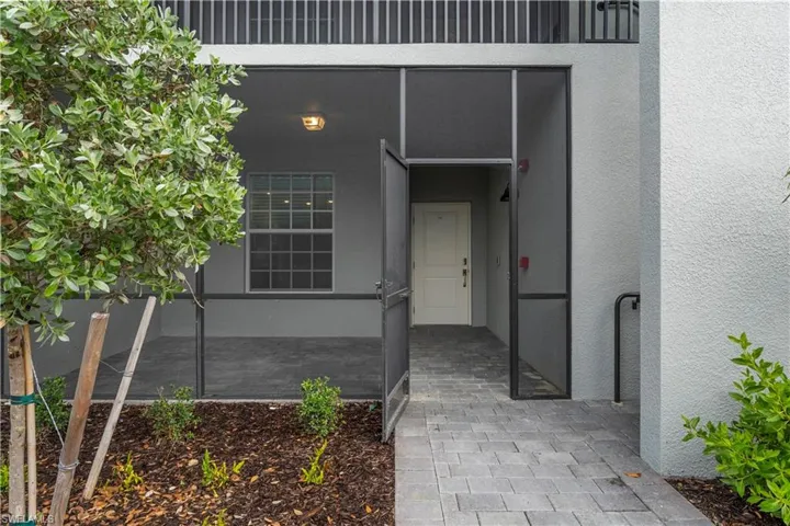 Screened-in entry with paver walkway, contemporary exterior lighting, and stucco finish