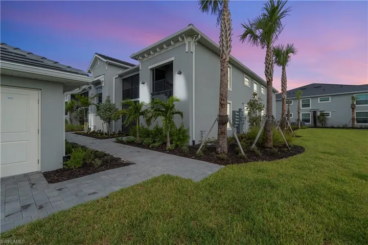 Contemporary architecture featuring a stucco exterior, paver walkways, manicured landscaping, and mature palm trees