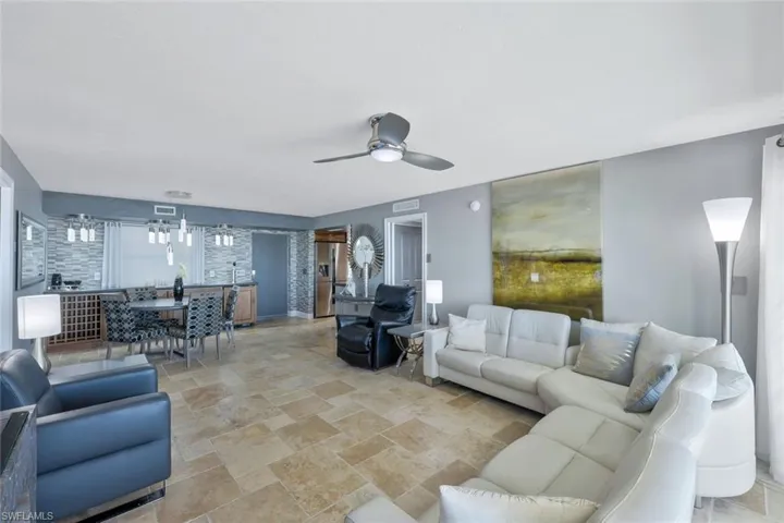 Living area with visible vents, stone finish flooring, and ceiling fan