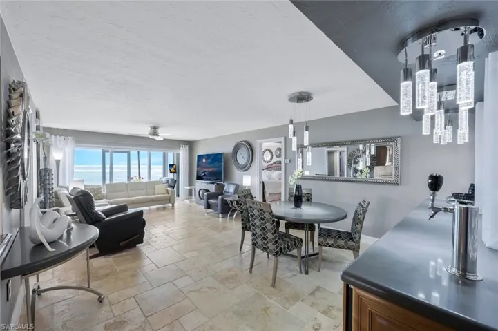 Dining area with stone tile floors, a ceiling fan, baseboards, and a textured ceiling