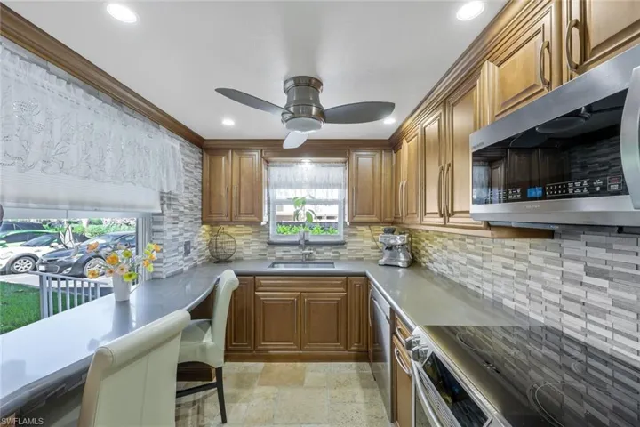 Kitchen with a sink, stone tile flooring, brown cabinetry, and stainless steel appliances