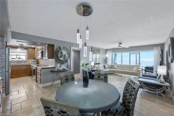 Dining space with visible vents, a ceiling fan, a textured ceiling, stone tile flooring, and baseboards