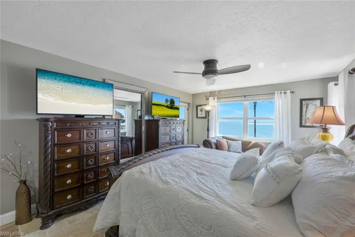 Bedroom featuring baseboards, stone finish floor, a textured ceiling, and a ceiling fan